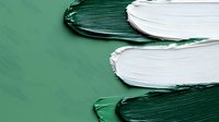 Abstract green and white paint strokes creating dynamic texture on surface. Bold brushstrokes showcase contrasting colors in modern artistic composition. Suitable for backgrounds.