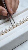 Jeweler using tweezers to sort lustrous white pearls in a velvet display tray, showcasing luxury craftsmanship and quality gemstone selection.