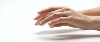 Female hands with manicured nails positioned gracefully above white surface in elegant gesture. Clean minimalist composition for beauty and skincare concepts.