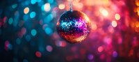 Sparkling disco ball reflecting colorful lights against blurred bokeh background in pink and blue tones creates festive party atmosphere. Perfect for nightclub promotion.