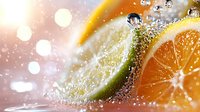 Fresh citrus slices of orange and lime with water drops and bubbles in bright sunlight, macro photography with bokeh effect and sparkles.