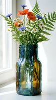 Wildflower bouquet with orange poppies, blue cornflowers, white daisies and green ferns in colorful glass vase on windowsill for home decor and floral arrangements.