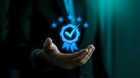 Business professional hand presenting glowing quality assurance badge with five stars and checkmark symbol for certification and excellence standards.