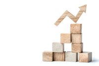 Wooden blocks stacked in ascending stairs formation with upward trending arrow shape on top, symbolizing growth and success on white background.