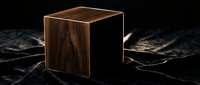 Wooden cube with dark walnut finish on black textured surface, isolated for design and branding projects.