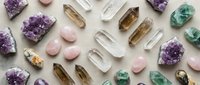 Collection of healing crystals and gemstones including amethyst, rose quartz, clear quartz and fluorite arranged on white background for wellness practices.