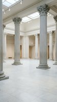 Grand neoclassical interior with ornate Corinthian columns and marble floors in museum or government building with natural skylight illumination.
