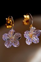 Crystal flower earrings with gold hooks featuring delicate purple-tinted petals and sparkling centers against dark background, elegant jewelry macro shot.