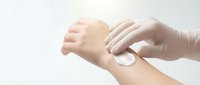Hands applying white cream or lotion to skin for skincare, cosmetics, dermatology, or beauty treatment purposes.