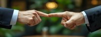 Two business people in formal suits pointing index fingers at each other against blurred green background, symbolizing confrontation, blame or conflict in workplace.