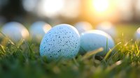Speckled blue Easter eggs nestled in fresh spring grass with soft bokeh sunlight, creating magical holiday atmosphere for seasonal celebrations and decorations.