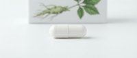 Two white oval pills or capsules displayed on a clean surface with botanical leaf illustration in background, representing natural medicine, herbal supplements, or pharmaceutical wellness products.