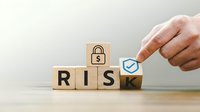 Business hand placing checkmark on wooden blocks spelling RISK with padlock symbol for security management and assessment strategies.