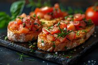 Fresh bruschetta with diced tomatoes, herbs and olive oil served on crusty baguette slices. Elegant Italian appetizer on dark stone board perfect for restaurant menu or cooking blog.