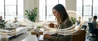 Young professional woman working on laptop in modern office with flowing light trails representing digital connectivity and data flow.