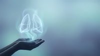 Glowing translucent lungs floating above open palm against soft blue gradient background. Medical healthcare concept for respiratory system awareness and lung health.