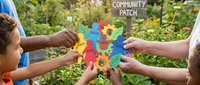 Two diverse children and an adult holding colorful puzzle pieces together at a community garden patch, symbolizing teamwork, unity, and environmental education for sustainable living projects.