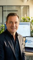 Confident middle-aged Caucasian businessman smiling in modern office with computer and plants creating professional corporate atmosphere.