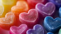Colorful heart shaped gummy candies in rainbow colors with sugar coating macro close up. Sweet treats arrangement on dark background for Valentine's day or romantic design.