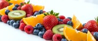 Fresh mixed berries and citrus fruits arranged on white background for healthy eating and nutrition concepts.