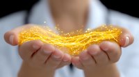 Glowing magical energy flows between cupped hands against dark background, showing bright yellow light trails and sparkles floating in gentle wave pattern.