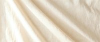 Luxurious cream silk fabric with elegant diagonal folds and soft lighting creating sophisticated textile background for fashion and interior design projects.