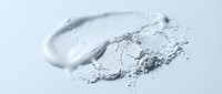 Crushed white powder and smeared cosmetic product on light background, suitable for beauty, skincare, and makeup advertising campaigns.