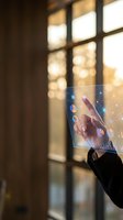 Hand holding transparent digital display with interactive data visualization and glowing icons near window with warm natural light, representing future technology, augmented reality, and business innovation.