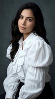 Young woman with long black hair and Latin American ethnicity wearing white ruffled blouse against gray background. Corporate and professional portrait for business, fashion, and lifestyle projects.