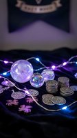 Mystical fortune telling setup with crystal balls, ancient coins and glowing LED lights creating magical atmosphere for divination and spiritual practices.