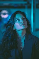Young professional woman with long dark hair looking up thoughtfully in modern office with blue neon lighting. Business portrait for corporate concepts.