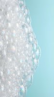 Iridescent soap bubbles foam texture with rainbow reflections on soft turquoise background for skincare cosmetics and spa wellness design concepts.