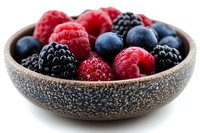 Fresh mixed berries including raspberries, blackberries and blueberries in textured stone bowl against white background, macro food photography for healthy eating.