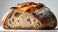 Freshly baked artisan sourdough bread with crispy crust and airy crumb structure, cut in half to show texture and air pockets.