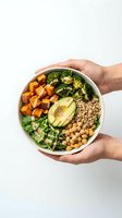 Hands holding white bowl with roasted sweet potato, broccoli, quinoa, chickpeas, avocado and greens. Nutritious meal prep bowl for healthy eating and balanced diet.