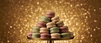 Colorful French macarons stacked on elegant stand against golden bokeh background for luxury dessert presentations and gourmet bakery marketing materials.