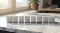 Wooden letter blocks spelling SERVICES on marble surface in bright modern office interior with natural lighting and plants in background.