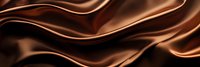 Luxurious flowing waves of smooth chocolate brown satin fabric create elegant abstract curves and folds against dark background. Suitable for confectionery packaging design.
