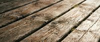 Weathered wooden deck planks with natural grain patterns and aging texture creating rustic surface for outdoor design projects.