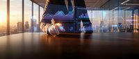 Businessman holding tablet with holographic data analytics and financial charts overlaying cityscape skyline at sunset, representing digital transformation and business intelligence.