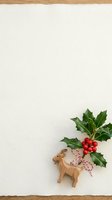 Wooden reindeer figurine with festive holly leaves and red berries on cream background with wood frame border, ideal for holiday greeting cards and seasonal marketing materials.