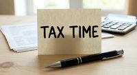 Tax time reminder note with calculator and pen on desk for accounting and financial planning during filing season.