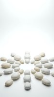 White and beige pills and capsules arranged in circular pattern on white background, isolated for pharmaceutical, healthcare, medicine, and wellness design projects.
