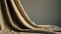 Luxurious beige velvet fabric draping elegantly with soft folds and rich texture, perfect for interior design and home decor projects.