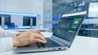 Caucasian professional using laptop with car fleet management dashboard software in modern office, monitoring vehicle data analytics.