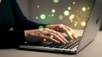 Professional hands typing on laptop with glowing digital particles and bokeh lights creating futuristic technology atmosphere for business presentations.