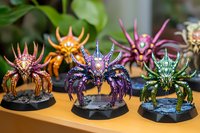 Colorful fantasy spider creatures with crystal details and metallic armor displayed on gaming bases. Painted miniatures showcase intricate details and vibrant designs.