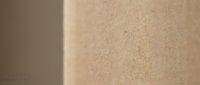 Warm beige textured wall surface with soft natural lighting creating gentle shadows and depth for interior design and architectural backgrounds.