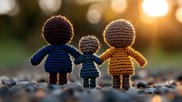 Handmade crochet family dolls holding hands at sunset representing love, unity and togetherness in warm golden light for crafts and emotional concepts.