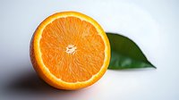Fresh juicy orange cut in half showing detailed pulp texture and natural citrus segments with green leaf on light background for healthy eating concept.